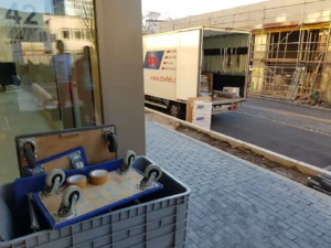 A view of a construction site with a truck delivering materials and a container on wheels in the foreground.