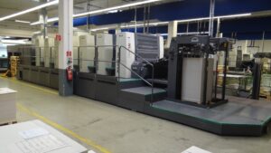 A large industrial printing press in a factory building.
