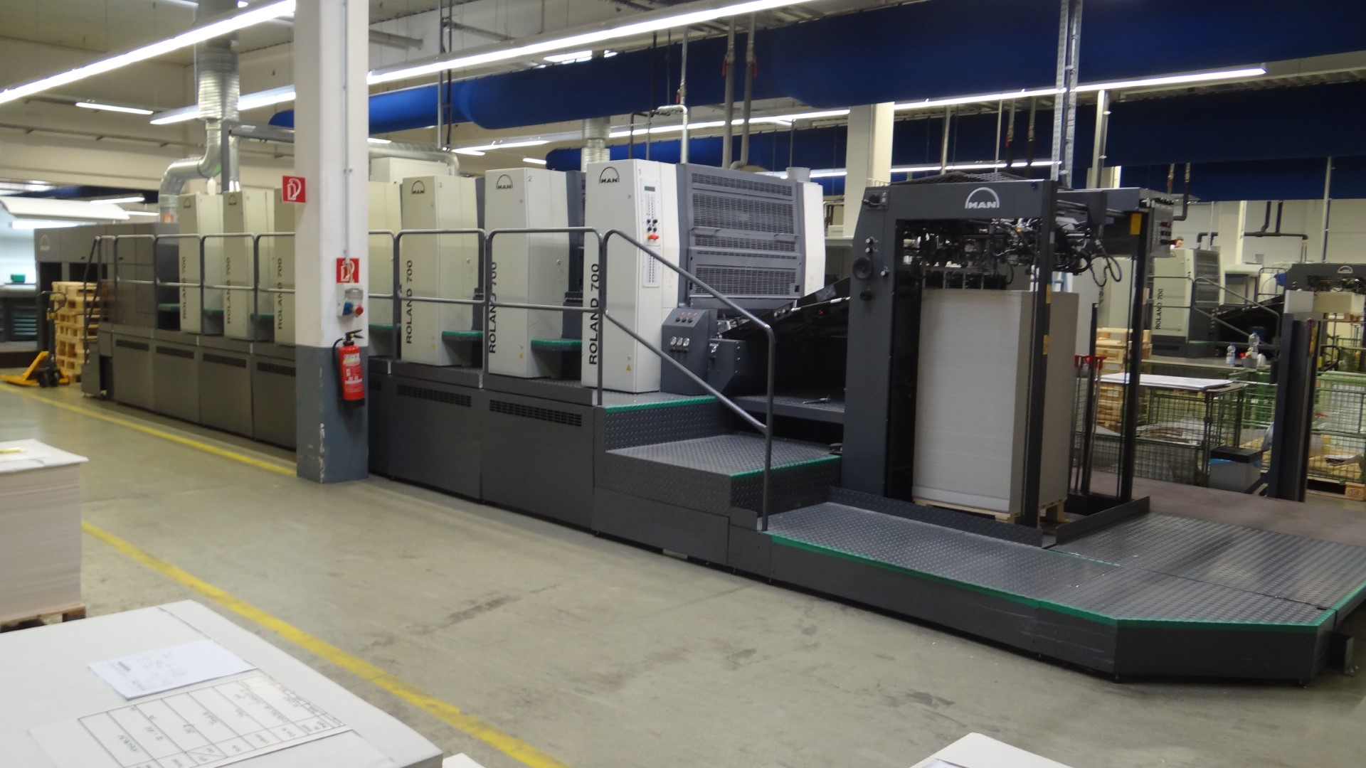 Große industrielle Druckmaschine in einer Fabrikhalle.