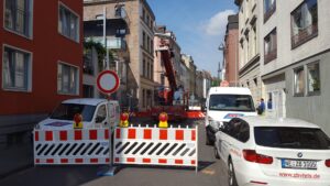 Road closure due to construction work on a narrow city street between residential buildings.