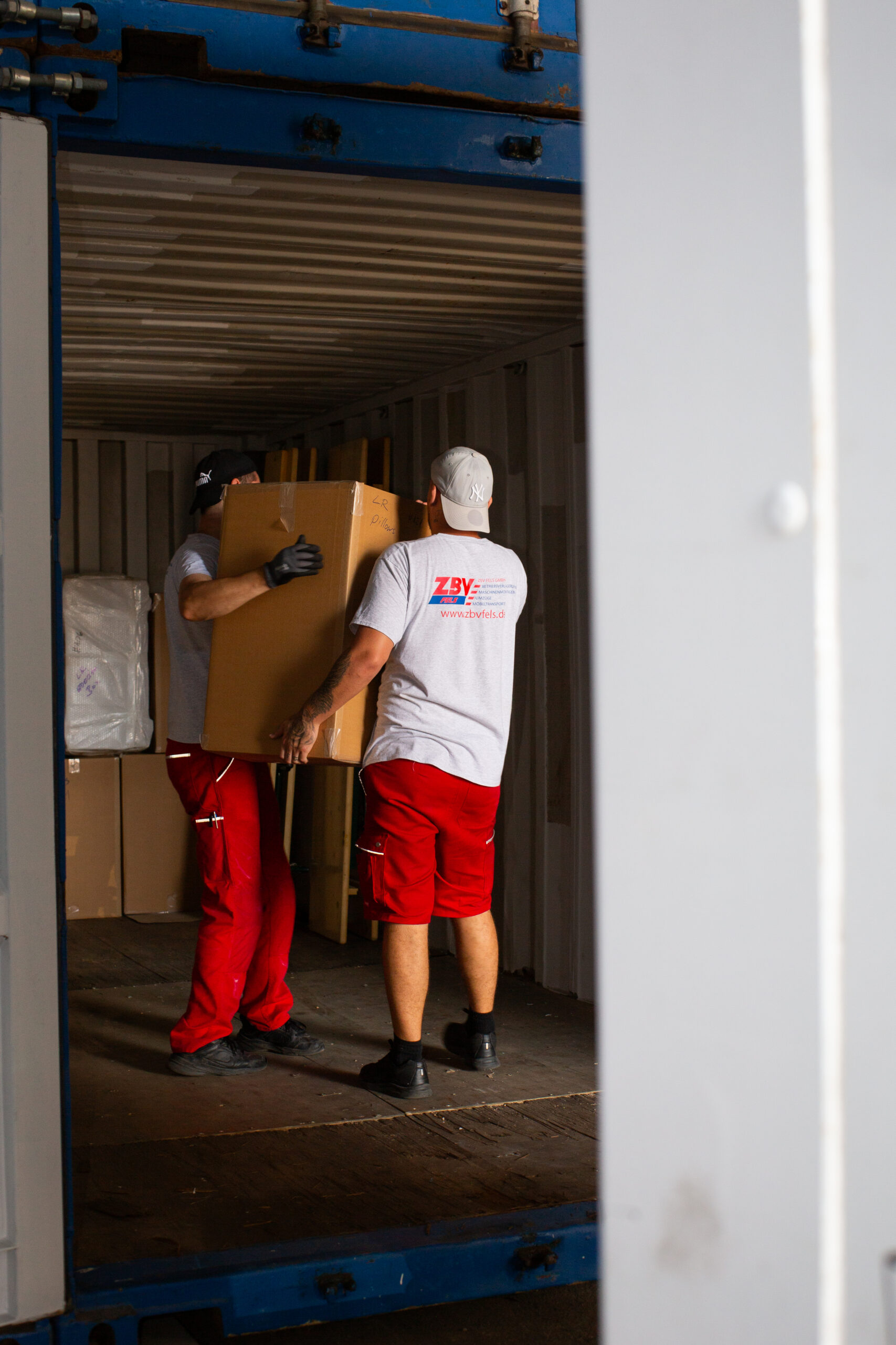 Zwei Männer laden Kartons in einen Container.