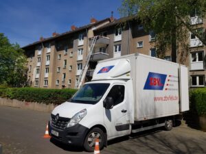 A delivery van with the ZBV logo in front of a residential building on a sunny day.