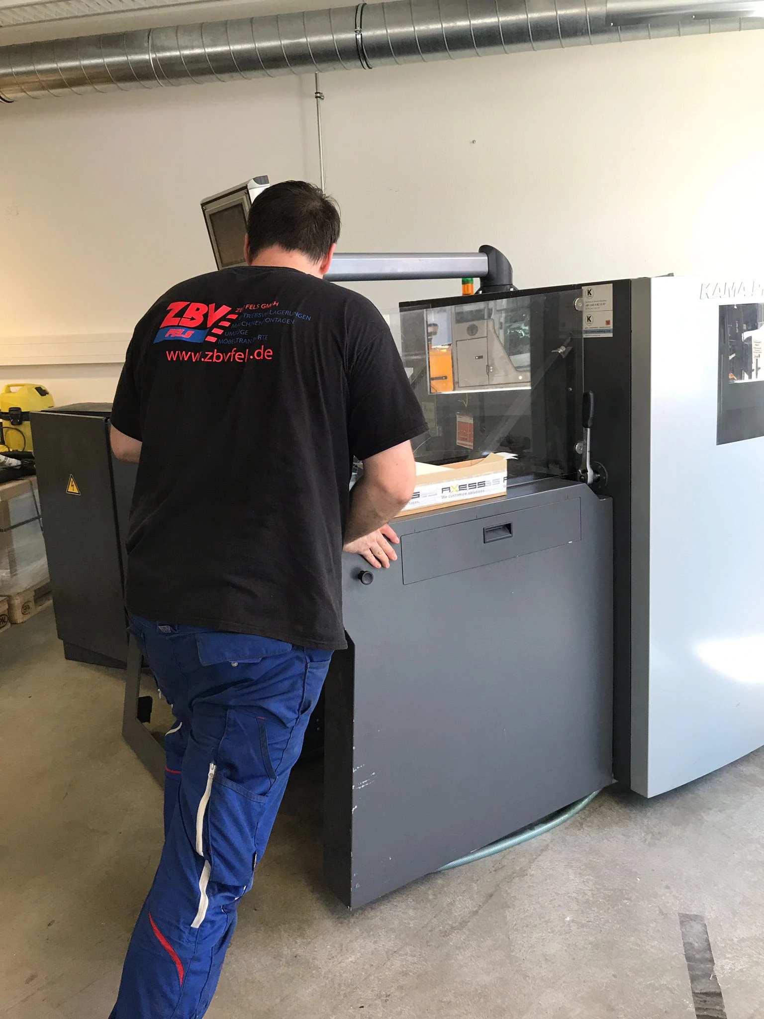Mann bedient eine große Druckmaschine in einer Werkstatt.