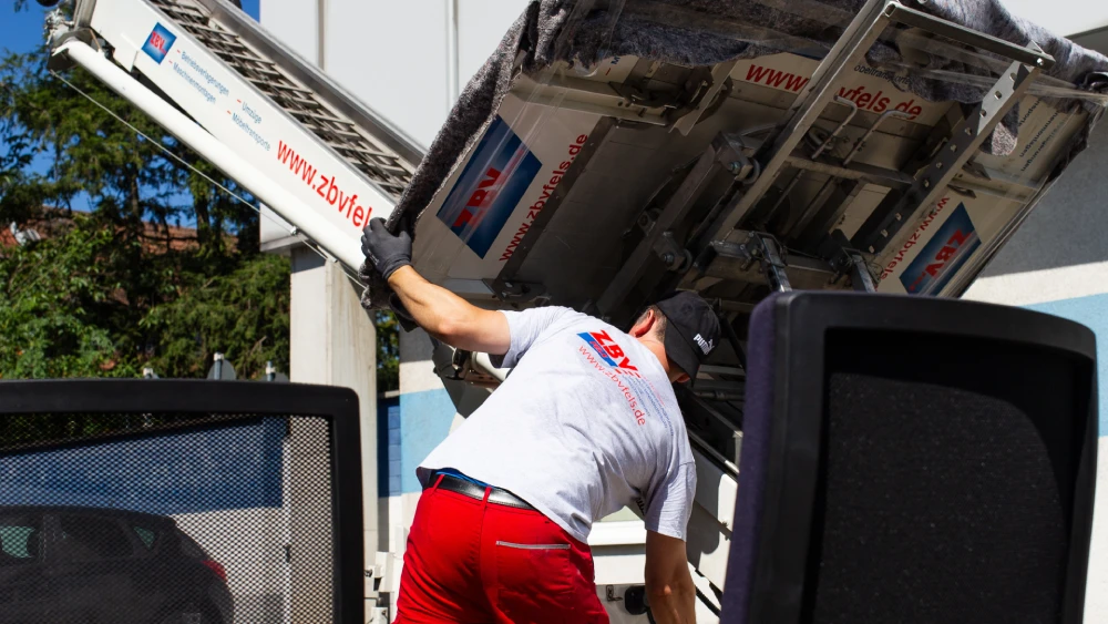Mann kippt Müllcontainer in LKW-Ladefläche.