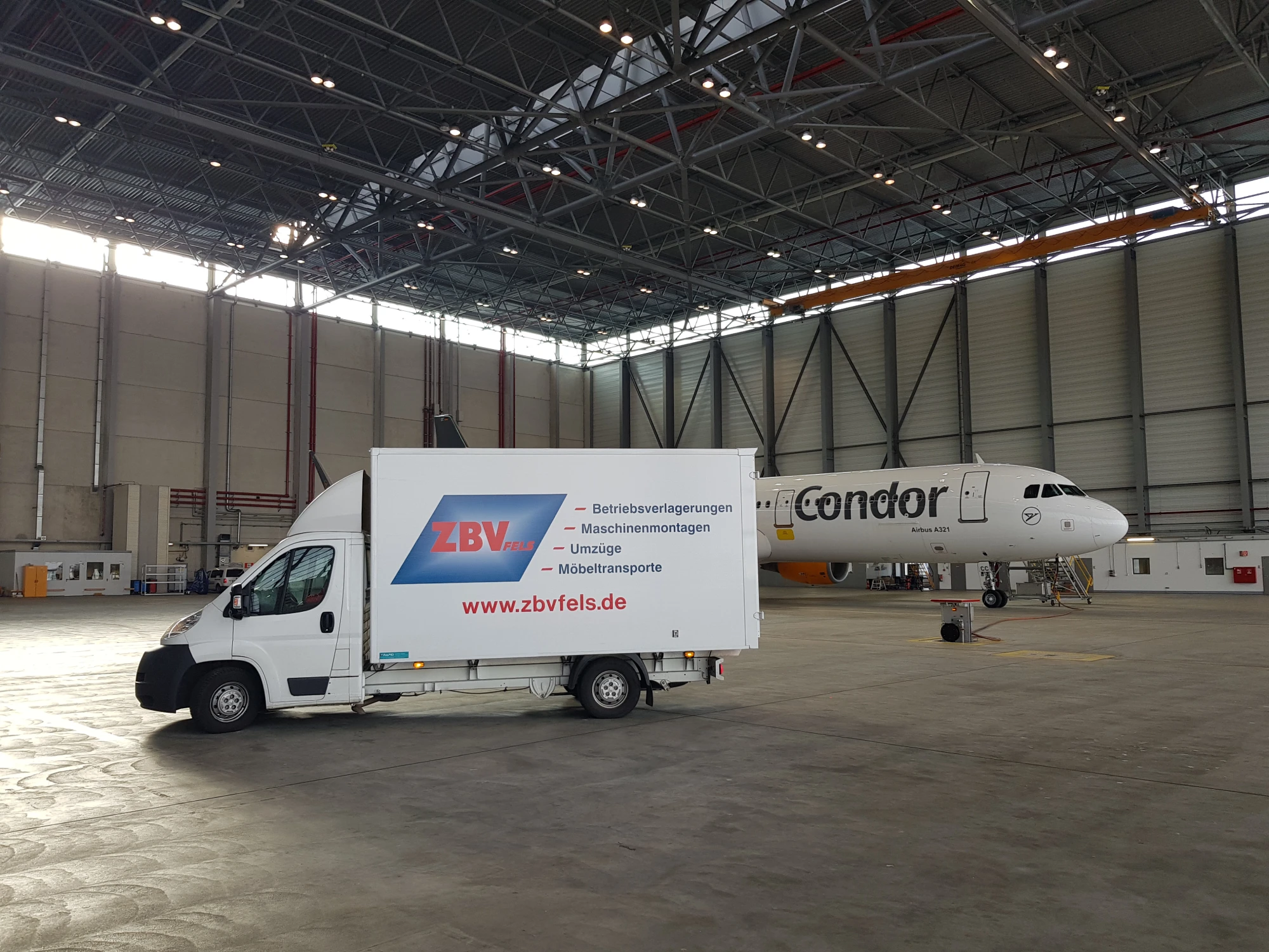 Transporter in Flugzeughangar neben geparktem Condor-Passagierflugzeug