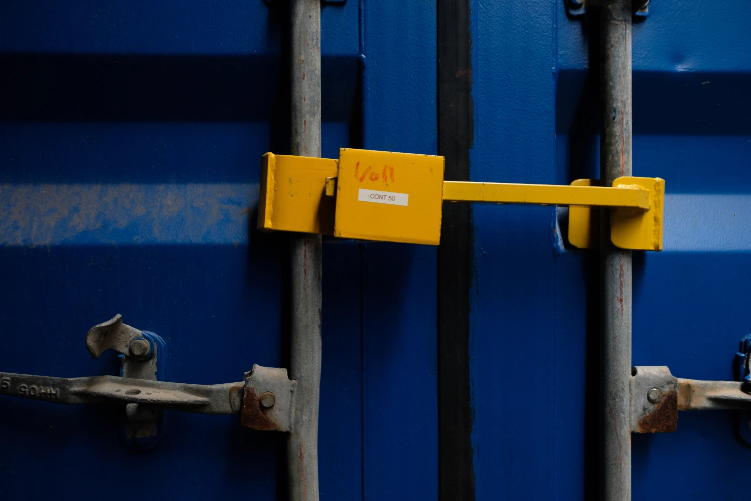 Blauer Container mit gelbem Vorhängeschloss an den Türgriffen.