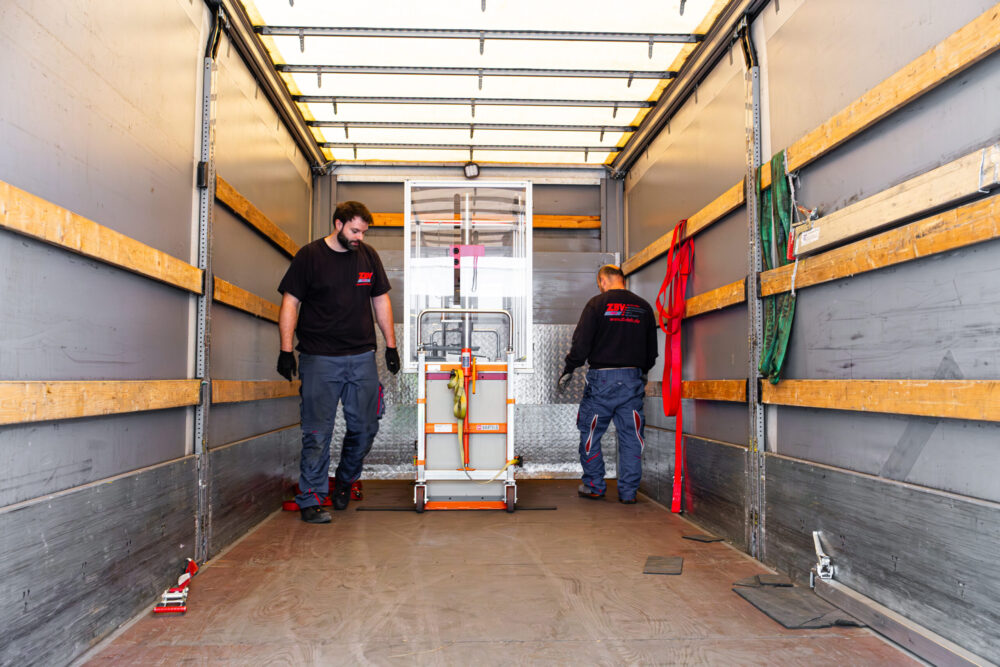 Zwei Mitarbeiter sichern Transportgerät in Lkw